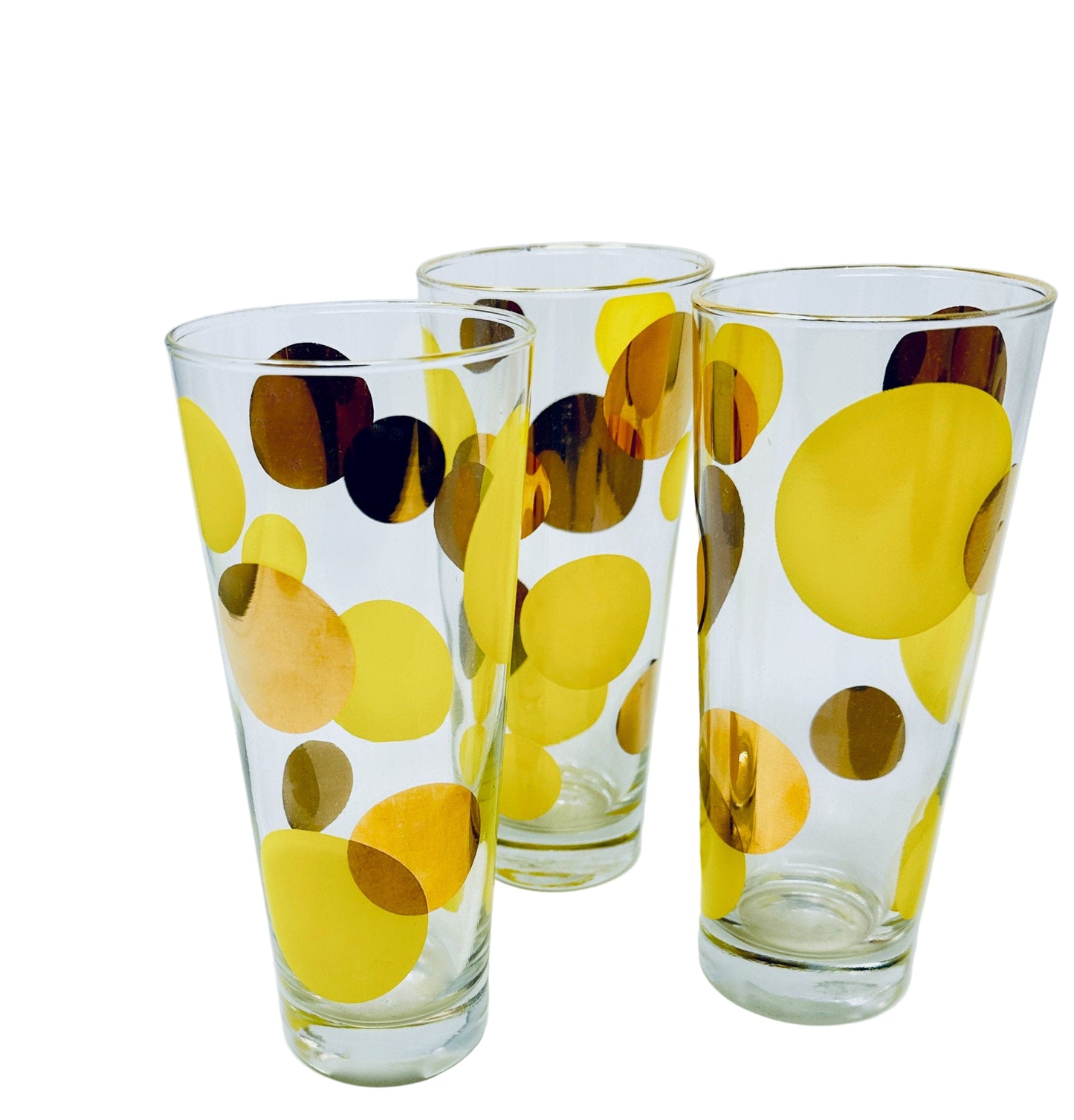 Three glass tumblers with yellow and brown polka dot patterns on a white background